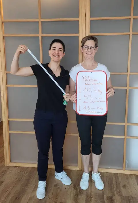 Une membre pose dans la salle du club avec son bilan écrit sur une ardoise blanche