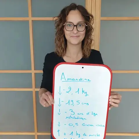 Une membre pose dans la salle du club avec son bilan écrit sur une ardoise blanche